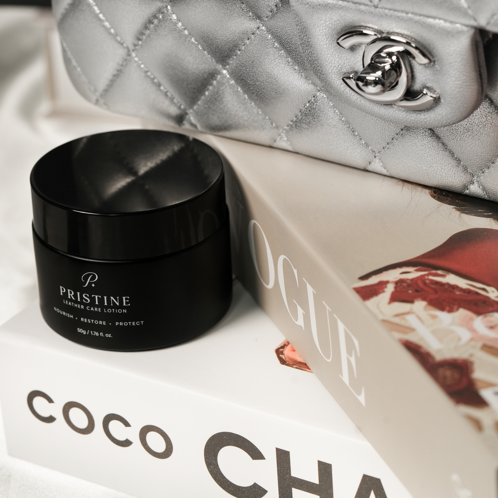 Angled view of PRISTINE Leather Care Lotion beside a silver quilted handbag.